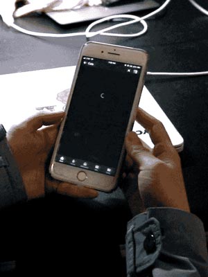 Hands holding an iPhone.  On the screen an app is loading while a spinning wheel animation plays.